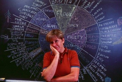 An image showing Ann Noble in front of a black board where she drew the wine aroma wheel by chalk.