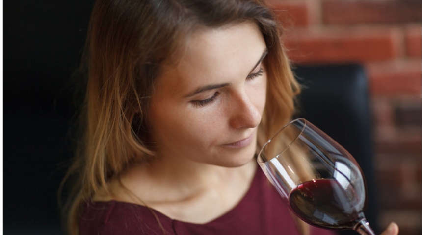 woman smells a glass of red wine